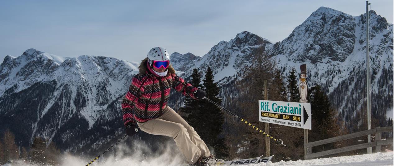 Eine Skifahrerin am Kronplatz; Dolomiten im Hintergrund.