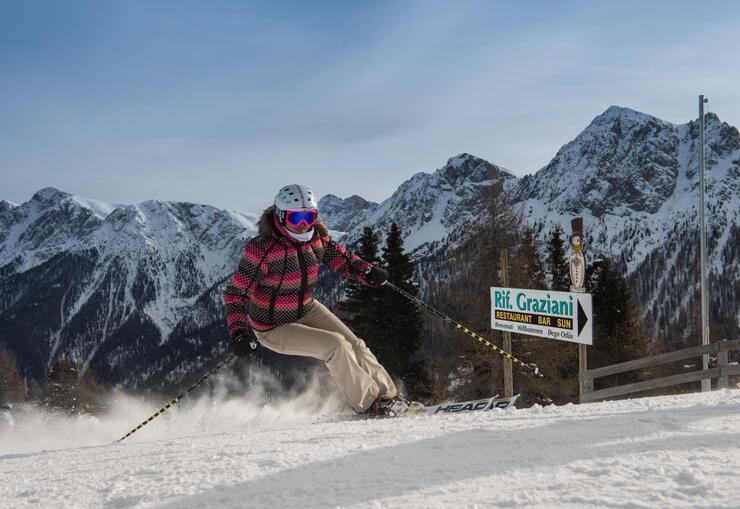 A female skier on Kronplatz; Dolomites in the background.