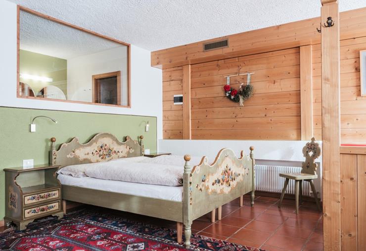 Schlafbereich des Familienzimmers mit Doppelbett und bemalten Holzmöbeln