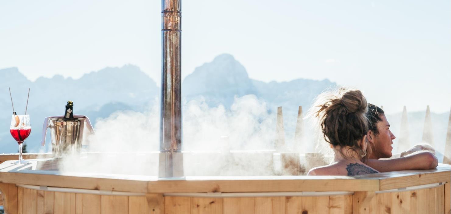 A couple in a hot tub with views of the Dolomites.