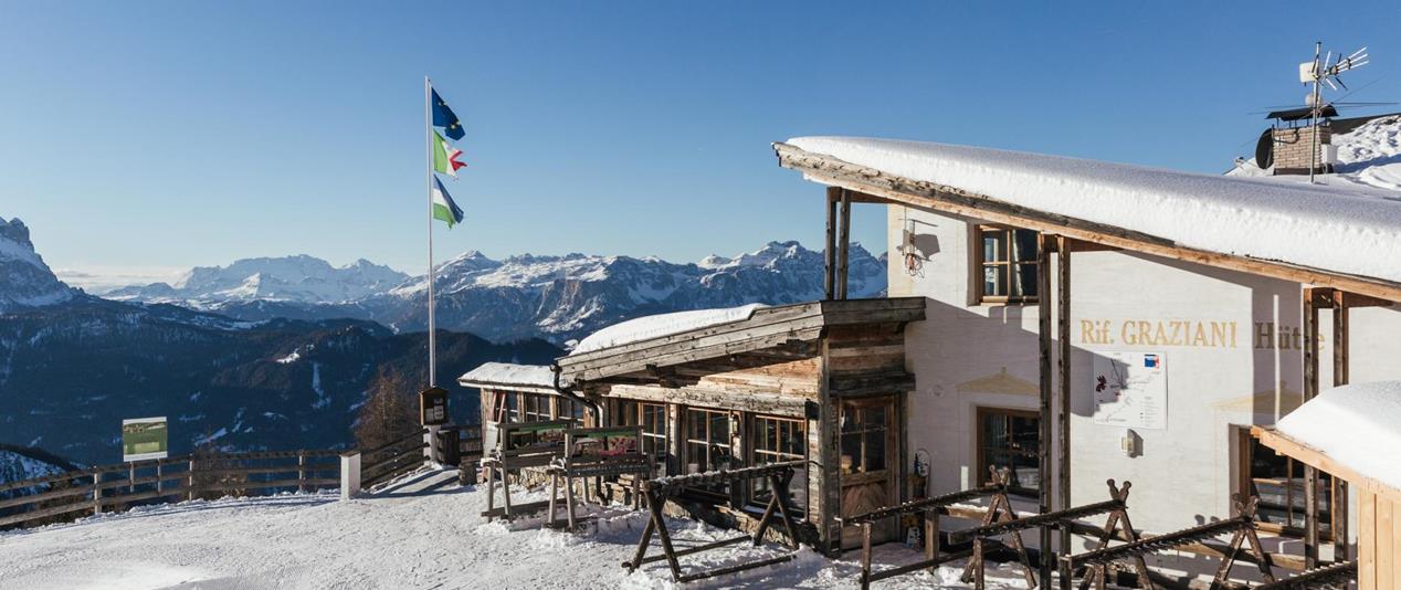 Graziani mountain hut in a snow-covered landscape with mountains in the background.