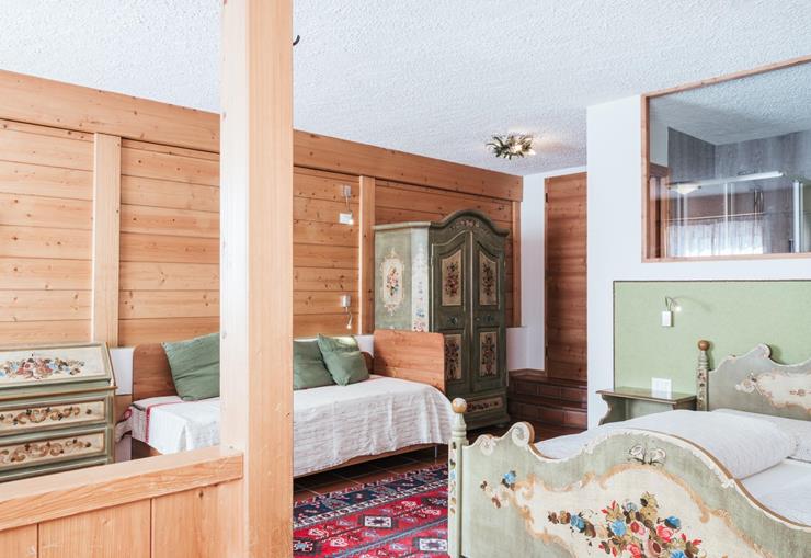Familienzimmer mit Holzwänden, Tagesbett, Doppelbett und bemalten Holzmöbeln