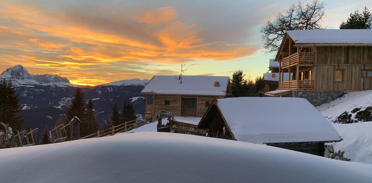 Winter sunset with the snow-covered Graziani mountain hut and chalets in the foreground.