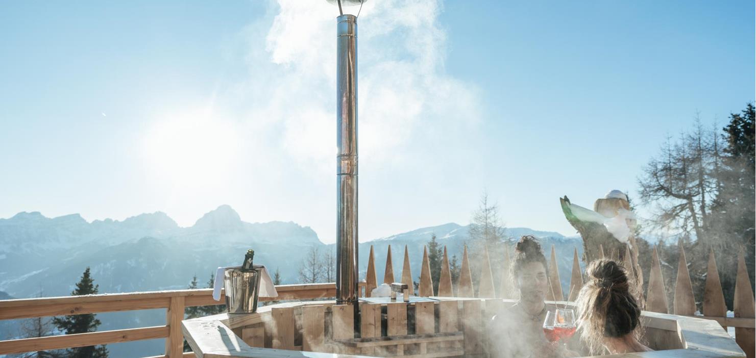 Ein Paar im Whirlpool mit Ausblick auf die umliegenden Berge