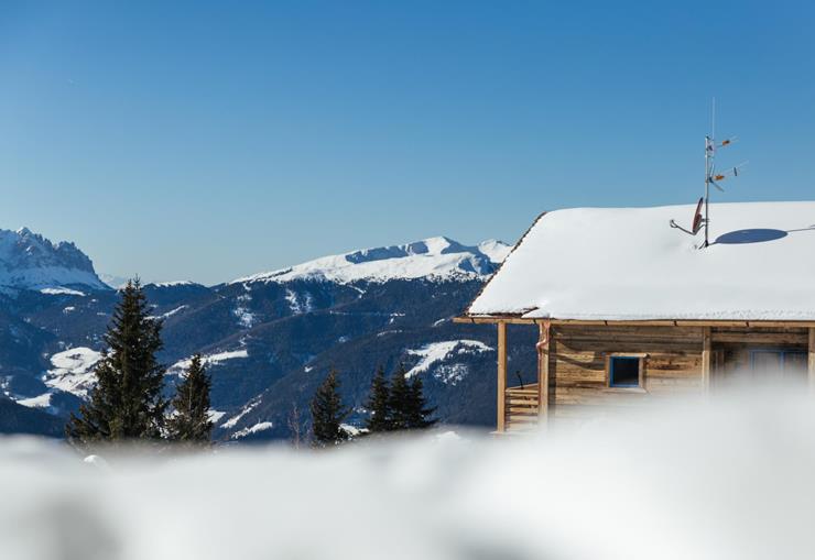 Holz-Chalet im Winter mit Blick auf die verschneite Dolomitenlandschaft.