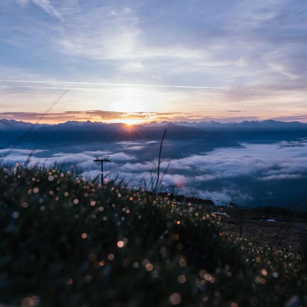 Sonnenaufgang über einer alpinen Berglandschaft mit Nebelmeer im Tal.