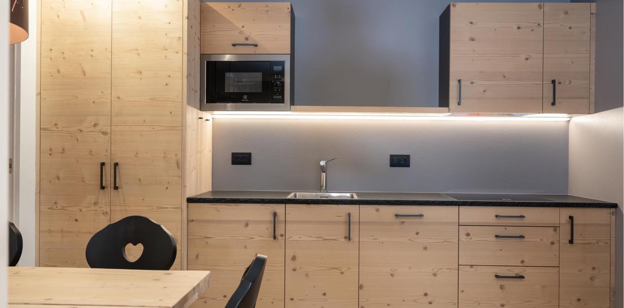 Kitchenette - CiasaKitchenette von Ciasa Arnica mit hellen Holzmöbeln, Esstisch und moderner Küchenzeile Arnica