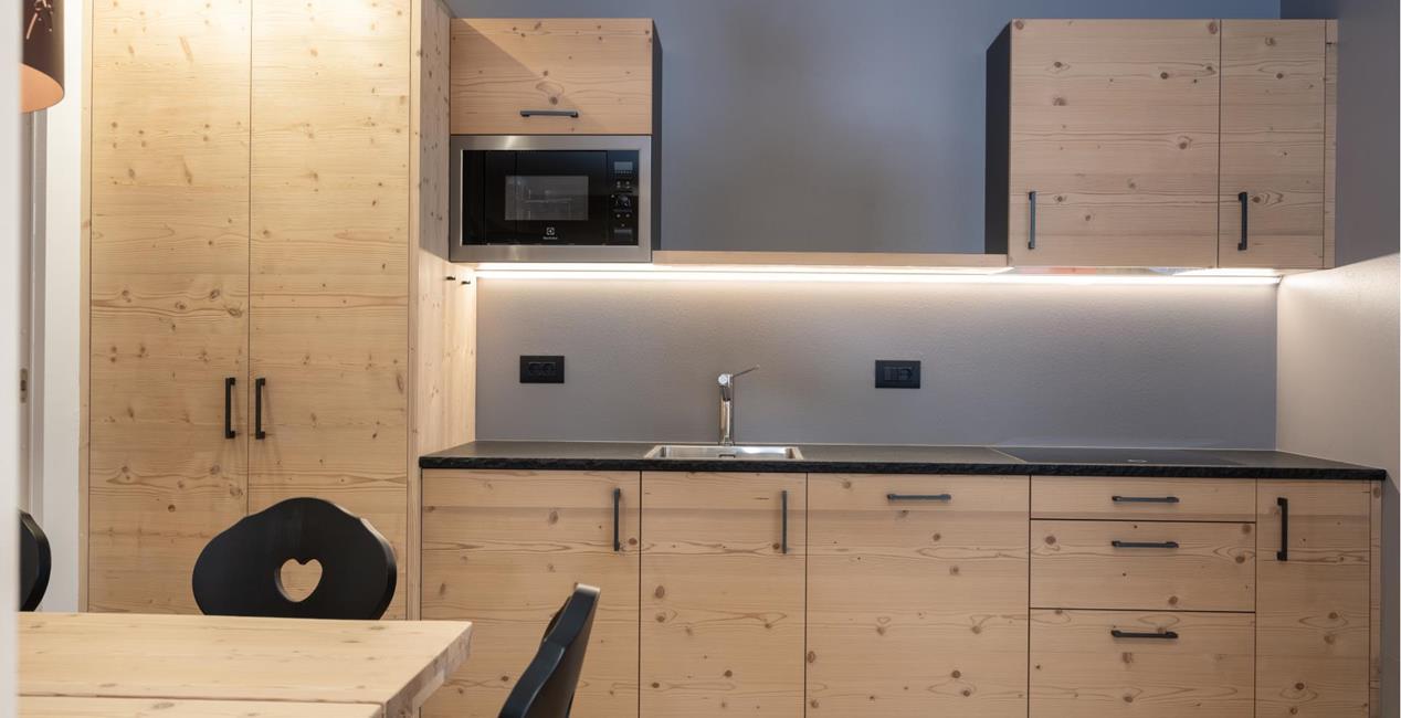 Kitchenette - CiasaKitchenette von Ciasa Arnica mit hellen Holzmöbeln, Esstisch und moderner Küchenzeile Arnica