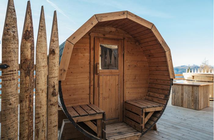 Sauna-Fass mit Whirlpool und Berglandschaft im Hintergrund.