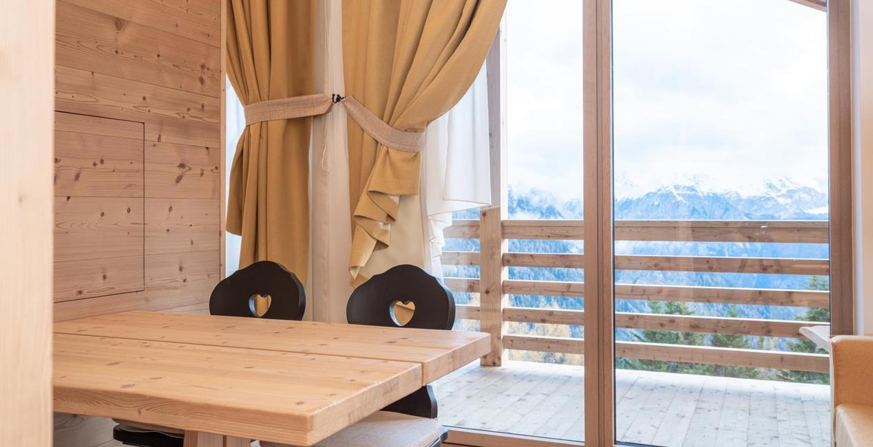 Living area with light wood furniture and balcony – Ciasa Arnica